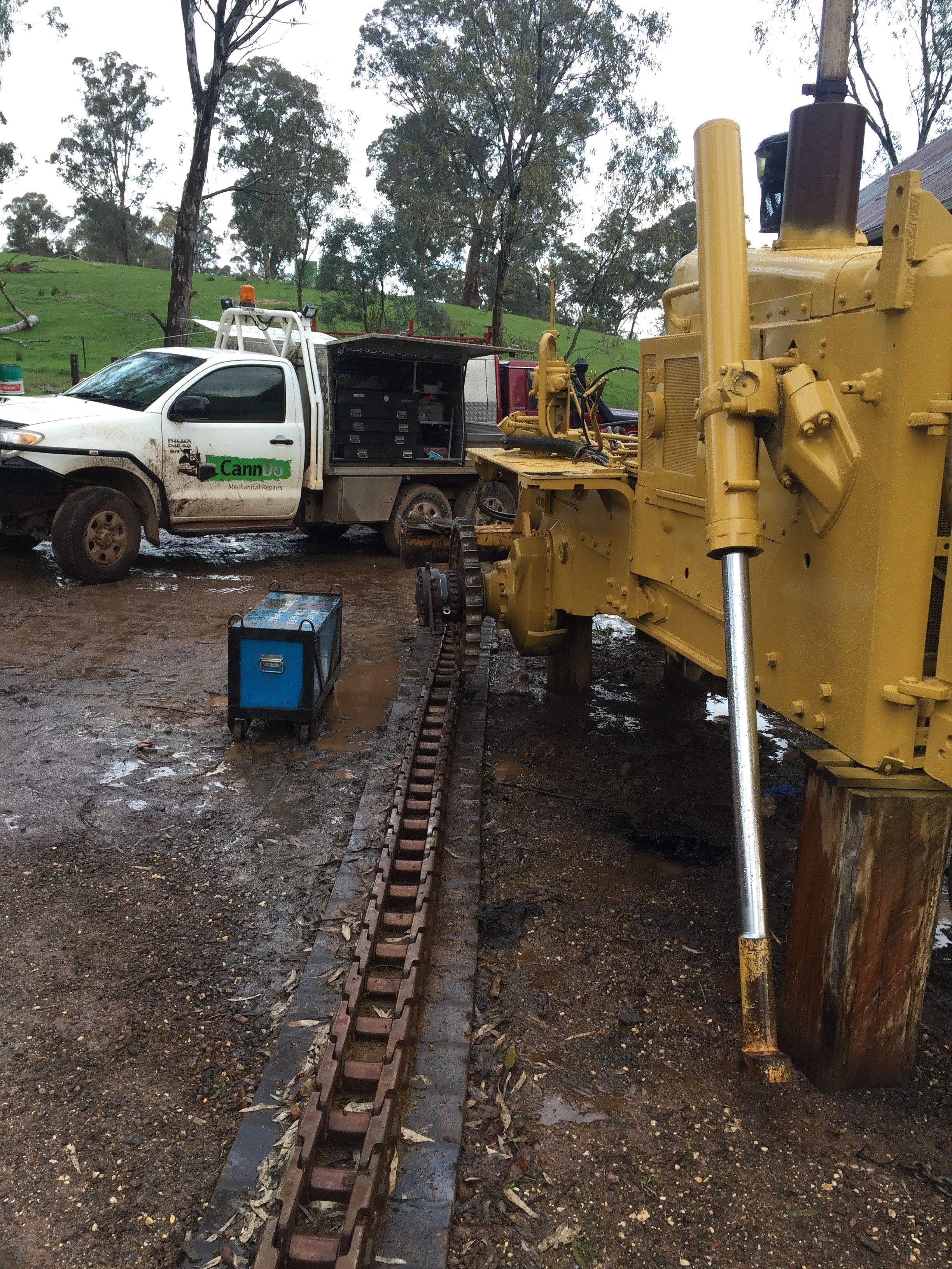 Yellow excavator with service truck on rural site