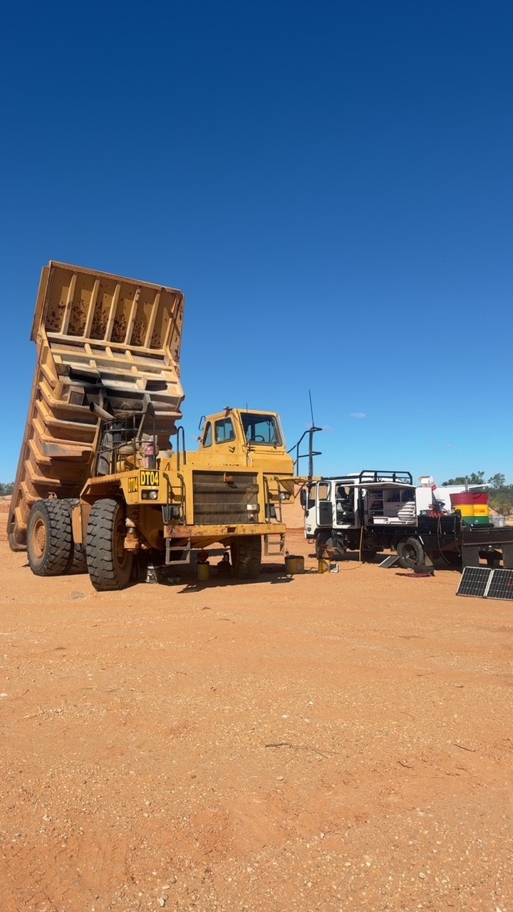 Rigid haul truck with Canndo service truck on red dirt site